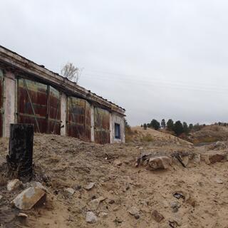 Rocks and sand outside a shuttered store house.