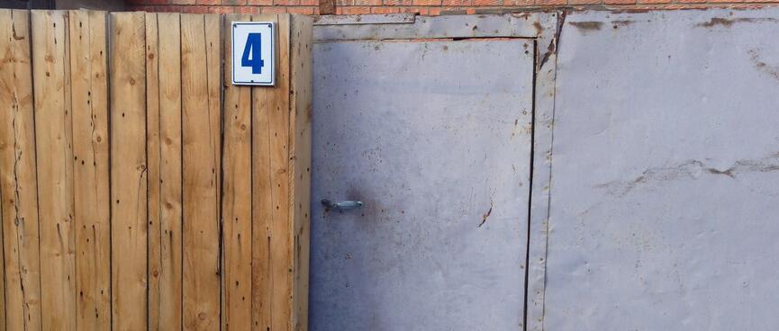 A battered metal door in front of a brick building.