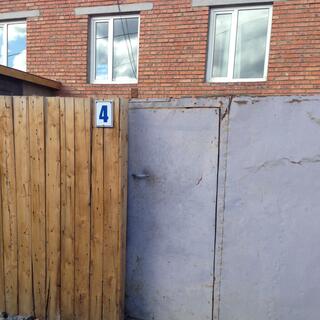 A battered metal door in front of a brick building.