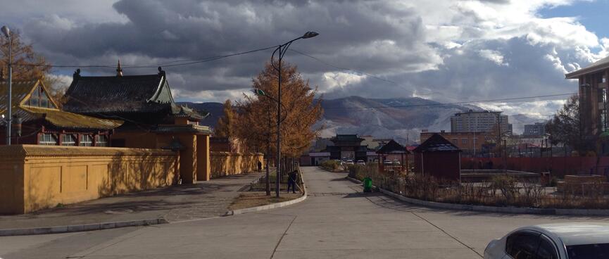 Snow dusted mountains tower above apartment blocks and temples.
