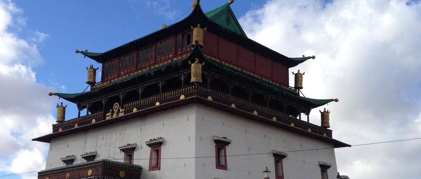 Multi story temple building constructed from white stone and brown wood.