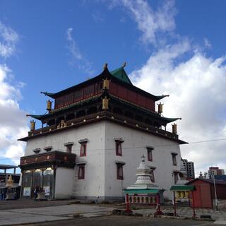 Multi story temple building constructed from white stone and brown wood.