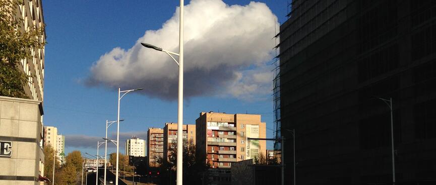 A puffy white cloud hangs above a set of completed apartment blocks and scaffolding around new development.