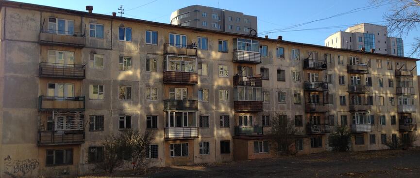 Older apartment buildings covered in weathered concrete and graffiti.