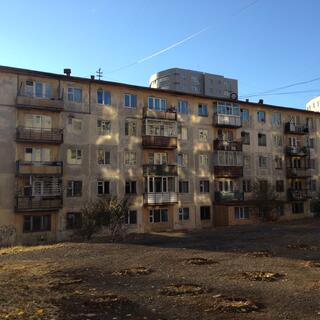 Older apartment buildings covered in weathered concrete and graffiti.