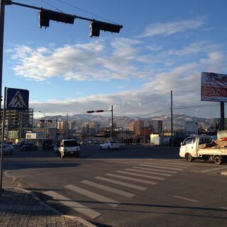 Views of apartment buildings and snowy mountains at a busy intersection.