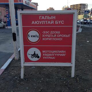Sign at a petrol station depicts 5 km/h speed limit and a speeding motor scooter.