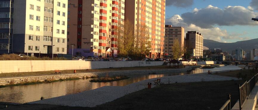 Tall apartment buildings on the edge of a gentrified river.