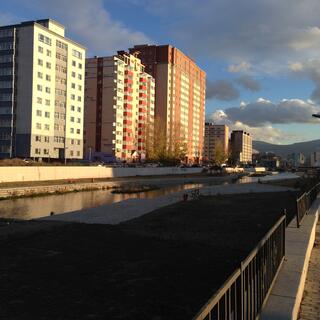 Tall apartment buildings on the edge of a gentrified river.