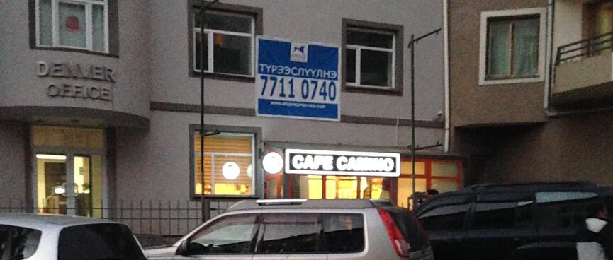 A neon sign for Cafe Camino at the entrance to a warmly lit interior.