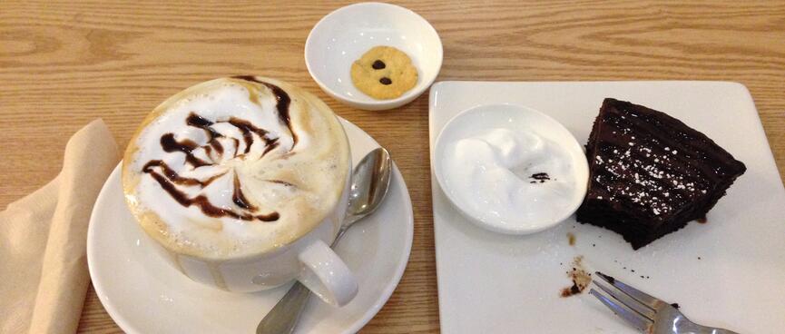 A cup of mocaccino and a slice of brownie with yoghurt.