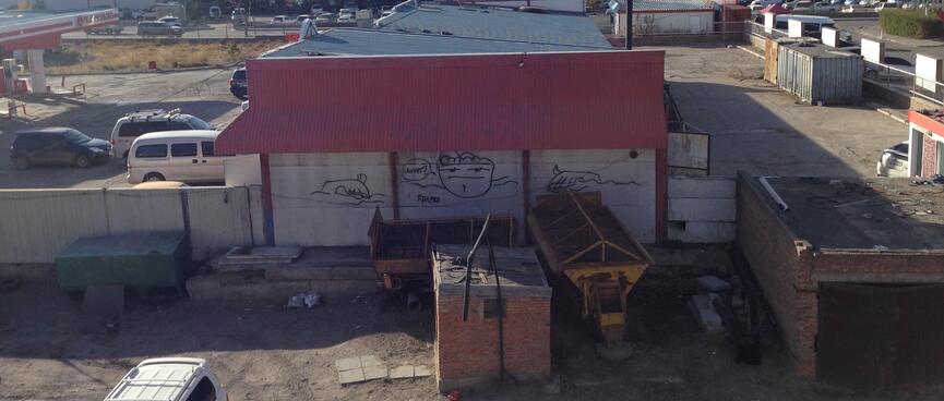 A graffiti sketch in an industrial area depicts a man saying 'What?'.