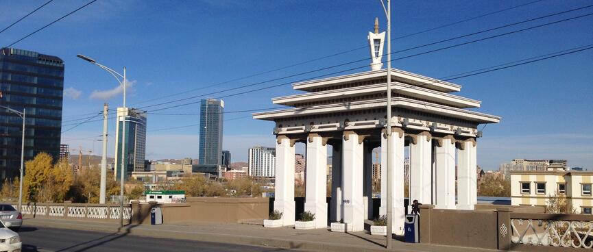 A small white open building with columns on a traffic bridge.