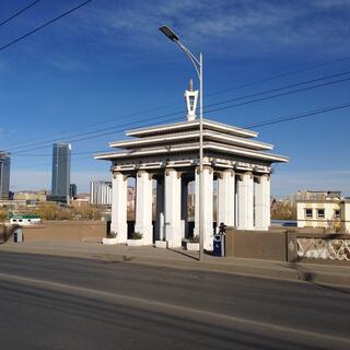 A small white open building with columns on a traffic bridge.