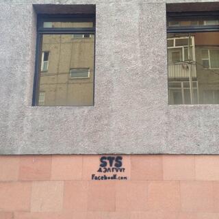 A website address spray painted on a building wall.
