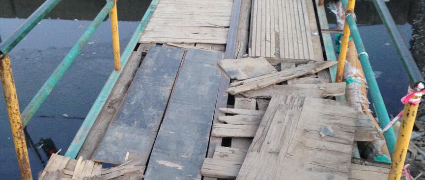 Loose bits of wood cover the metal bones of a pedestrian bridge.