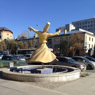A cream statue of a dancing man wearing a long skirt and a tall hat.