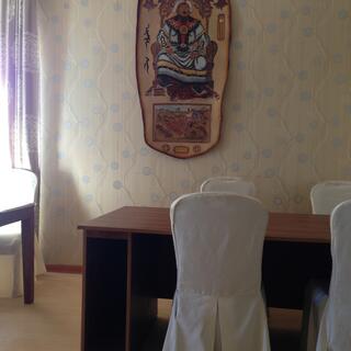 Neutral colour scheme, a wall hanging of Genghis Khan, white covered chairs and wooden tables.