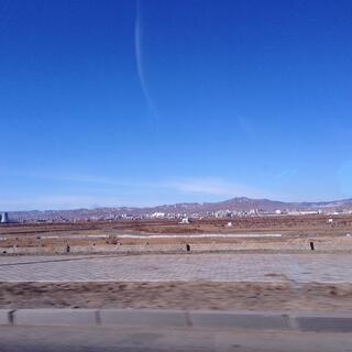 Empty steppes, a power plant and in the distance city buildings and low mountains.
