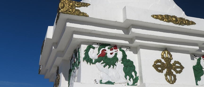 A stone monument is adorned with golden swirls and the figure of a white lion.