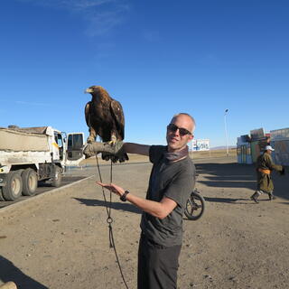 I look at the camera while an eagle perches on my forearm.