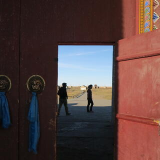 In a red entrance way, blue cloth hangs from two golden lion door handles.