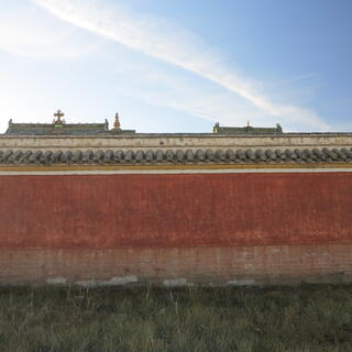 Rooftops are just visible over the top of a red wall.