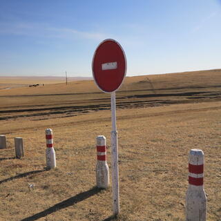 A No Entry sign and white fenceposts with red stripes.
