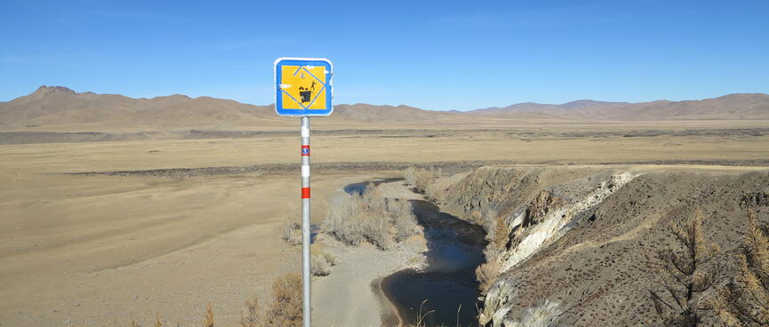 A sign depicts a ger, a tree and a man falling off a cliff.