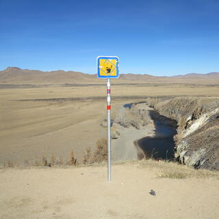 A sign depicts a ger, a tree and a man falling off a cliff.