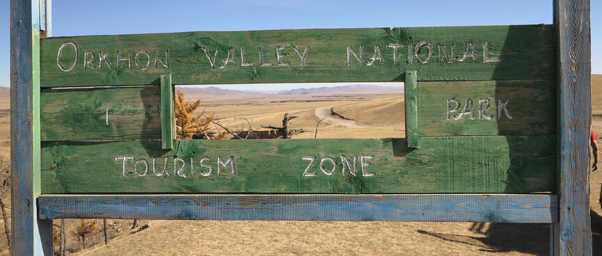 A green wooden sign with a rectangular hole in the centre.