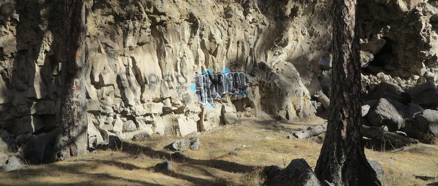 Spray painted graffiti on a natural rock wall.