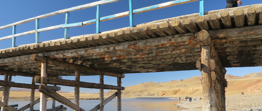 The underside of the bridge shows perpendicular logs and diagonal supports.