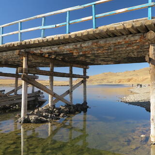 The underside of the bridge shows perpendicular logs and diagonal supports.