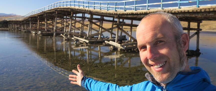 I stretch my arm out in front of a long wavy bridge.