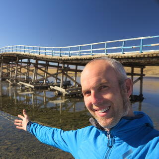 I stretch my arm out in front of a long wavy bridge.