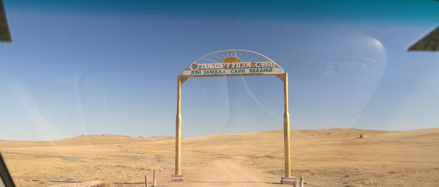 A simple wooden archway straddles a dirt road.