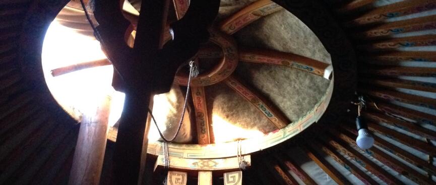 Looking up at a partially open ventilation hole in the center of the ger roof.