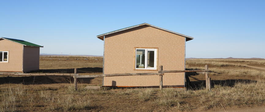 Identical windowed huts, light brown with green roofs.