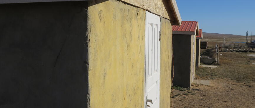 Identical windowless huts, yellow with red roofs.