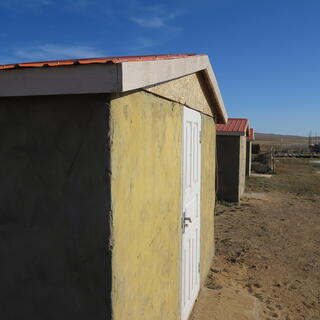 Identical windowless huts, yellow with red roofs.