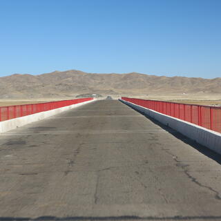 Red metal rails run along the sides of an asphalt road bridge.