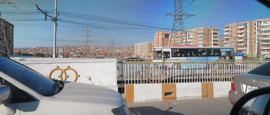 A busy landscape of cars, buses, high rises and houses.