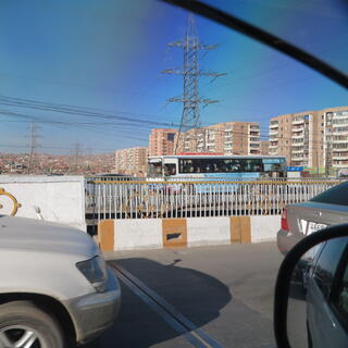 A busy landscape of cars, buses, high rises and houses.