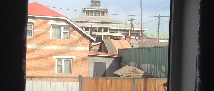 The view out of the window includes a tired two-storey house, half a shipping container and some low key construction.