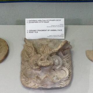 A ceramic fragment of an animal face roof tile resembles a tusked boar.