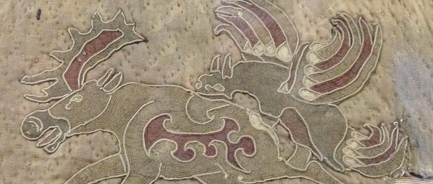 A sewn quilt features two running reindeer.