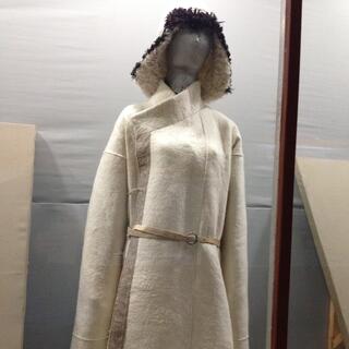 A mannequin wears a furry hat and a white cloak with light brown belt and trim.