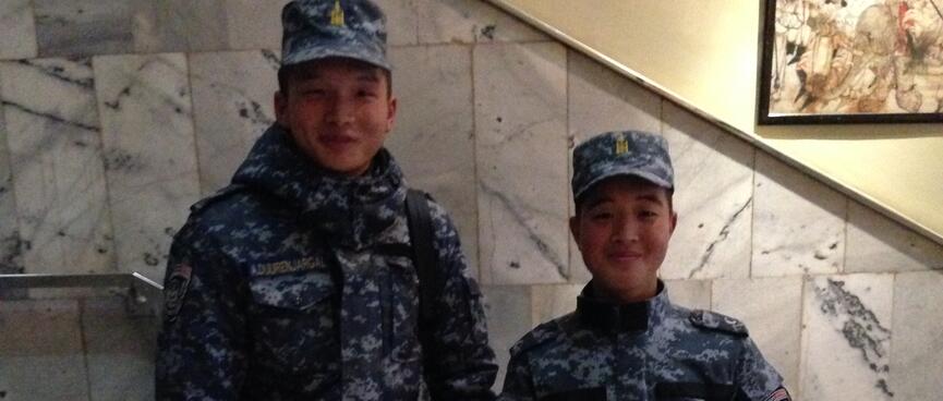 A smiling man and woman wearing camouflaged army fatigues.