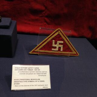 A sewn triangle badge with a gold swastika and border.